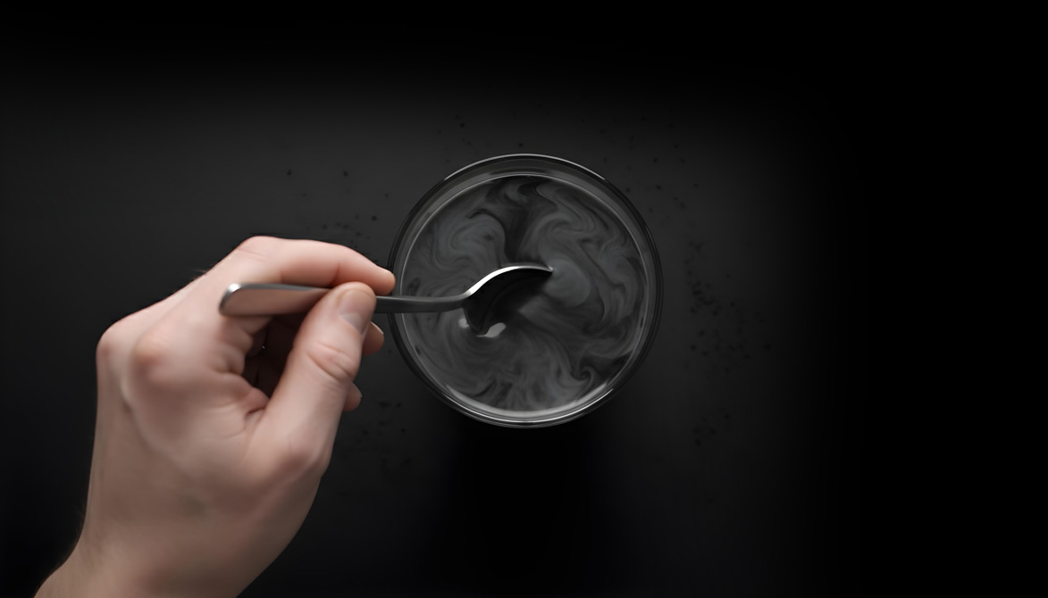 Hand stirring a dark mixture in a glass bowl