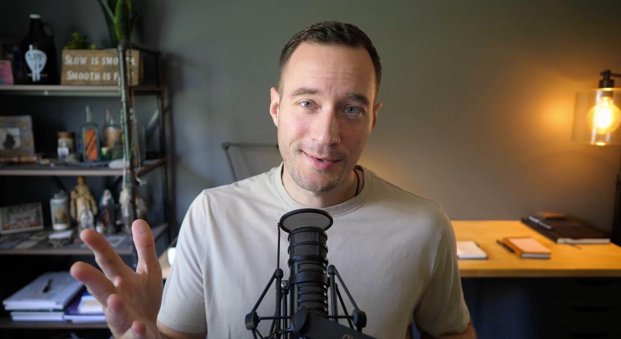 Mark Queppet at his desk, speaking into a microphone